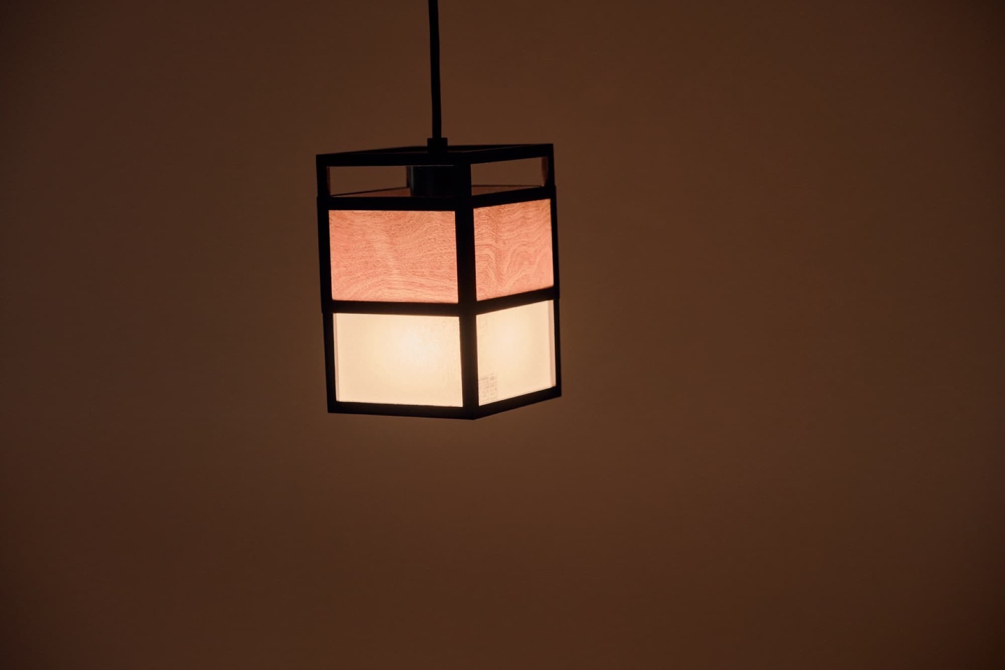 A wood-framed lantern glowing against a plaster wall