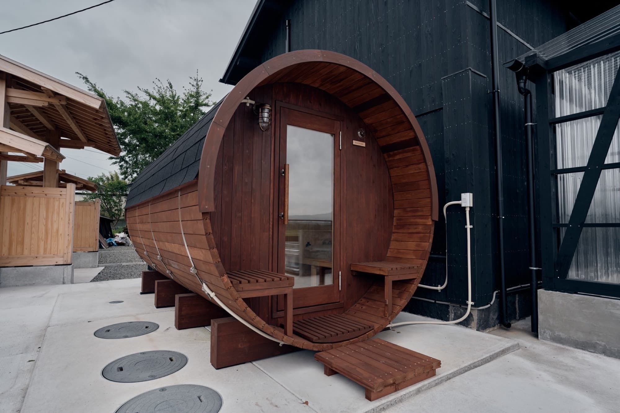 The cedar barrel sauna beside the charred-black wall